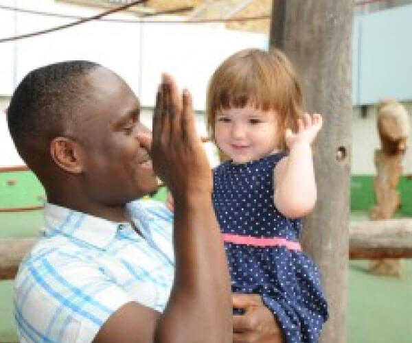 Man holding a small girl, about to high-five each other